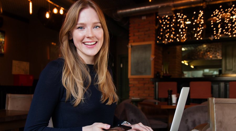 Selbständige Frau arbeitet lächelnd am Laptop