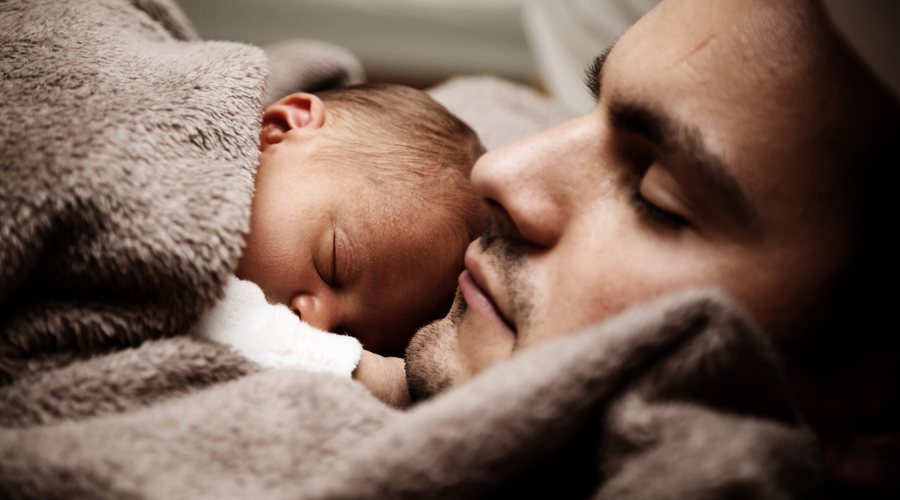 Vater mit schlafendem Neugeborenen